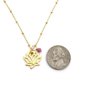 Openwork lotus pendant next to a nickel for size comparison. Pendant is approximately 15 by 15 mm, slightly smaller than the coin. Nickels measure approximately 21 mm in diameter.