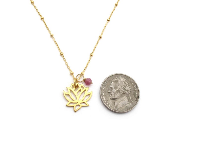 Openwork lotus pendant next to a nickel for size comparison. Pendant is approximately 15 by 15 mm, slightly smaller than the coin. Nickels measure approximately 21 mm in diameter.