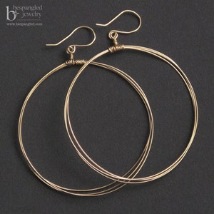 May include: A pair of gold hoop earrings with a double wire design. The earrings have a simple, elegant style.