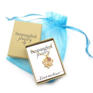 Bespangled Jewelry openwork gold lotus flower pendant necklace with pink tourmaline charm accent packaged in a small kraft jewelry gift box with teal organza pouch. Ready for gift-giving!

Necklace card says tourmaline with Bespangled logo.