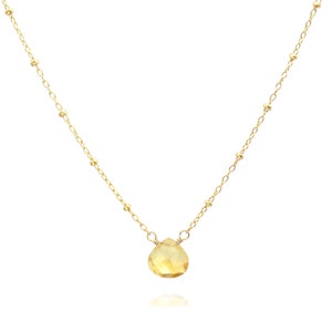 May include: A gold chain necklace with a single teardrop-shaped yellow gemstone pendant.