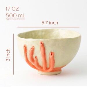 Puede incluir: Cuenco de cer&aacute;mica color crema con protuberancias color salm&oacute;n en forma de coral. El cuenco mide 14,5 cm de ancho y 7,6 cm de alto, con una capacidad de 500 ml. El cuenco hecho a mano tiene una superficie texturizada y un dise&ntilde;o &uacute;nico.
