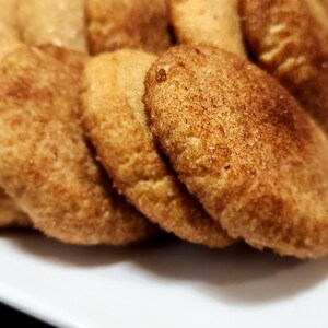 May include: A close-up of a plate of freshly baked cinnamon sugar cookies. The cookies are golden brown and have a slightly crispy texture.