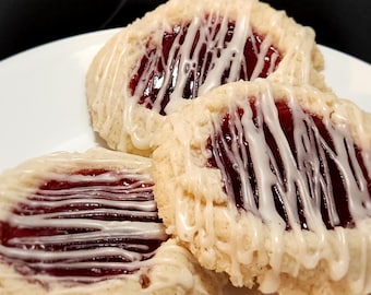 Könnte beinhalten: Drei hausgemachte Kekse mit einem weißen Zuckerguss und einer Füllung aus roter Himbeermarmelade.