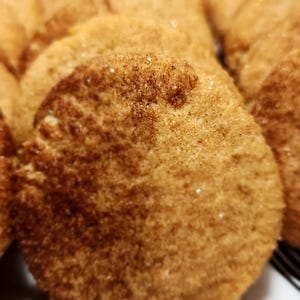 May include: A close-up of a stack of brown sugar cookies with a cinnamon sugar topping. The cookies are round and have a slightly crispy texture.