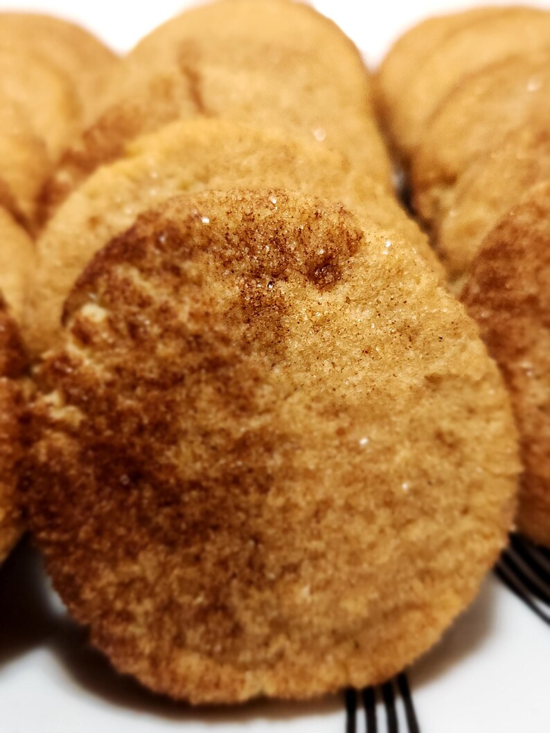 May include: A close-up of a stack of brown sugar cookies with a cinnamon sugar topping. The cookies are round and have a slightly crispy texture.