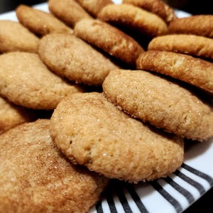 May include: A plate of freshly baked cinnamon sugar cookies. The cookies are golden brown and have a slightly crispy texture.