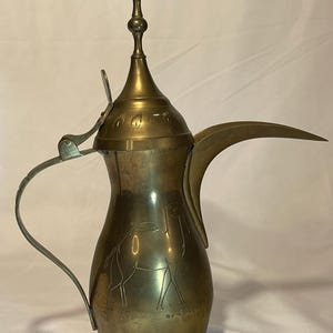 May include: A brass Arabic coffee pot with a camel design and a decorative lid. The pot has a spout and a handle.