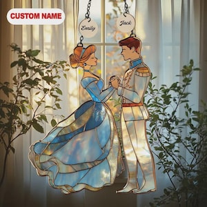 May include: Stained glass window hanging featuring a princess and prince in a romantic pose. The princess wears a blue gown, and the prince is in a white uniform. The names "Emily" and "Jack" are displayed on the hanging. The text "CUSTOM NAME" is also visible.