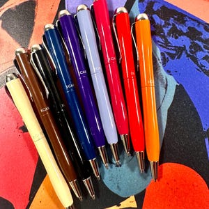 Puede incluir: Un conjunto de diez bolígrafos con detalles plateados y una variedad de colores, incluyendo blanco, marrón, negro, azul marino, morado, azul claro, rojo y naranja. Cada bolígrafo tiene la palabra "ICAR" impresa en el lateral.