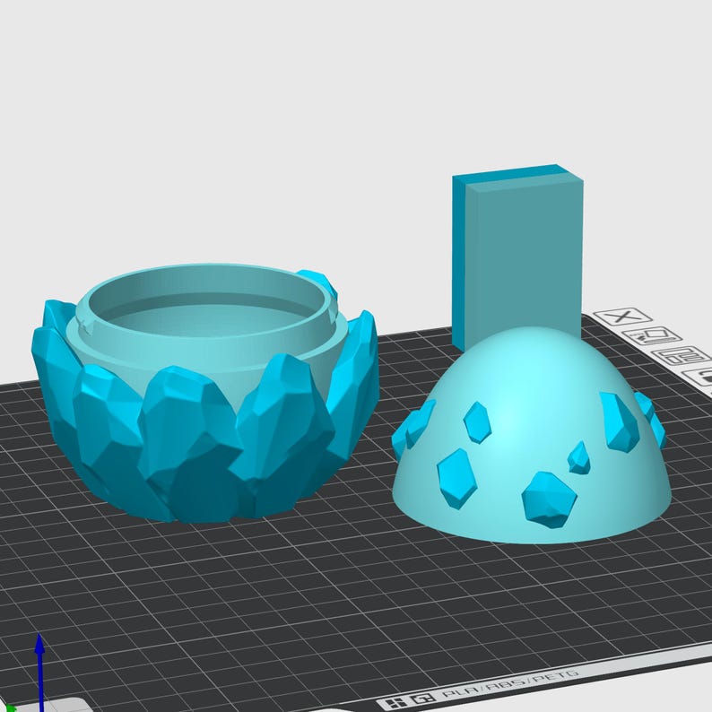 May include: A light blue, 3D printed, crystal-shaped container with a removable lid. The container is designed to look like a crystal or gem.