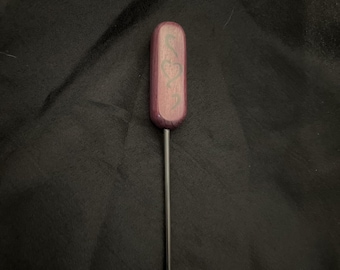May include: A wooden tool with a purple-stained handle and a long, thin metal shaft. The handle has a carved design.
