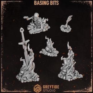May include: A set of grey resin basing bits featuring miniature gaming terrain elements including a skeleton emerging from the ground, a skeletal hand, a sword stuck in a pile of skulls and flames, and additional skull and flame debris.