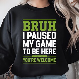 Pode incluir: Camisola de cor preta com texto verde que diz "BRUH I PAUSED MY GAME TO BE HERE YOU'RE WELCOME"