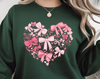 May include: A dark green sweatshirt with a pink heart-shaped design made up of bows and hearts.