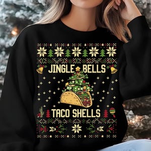 May include: Black sweatshirt with a Christmas-themed design featuring a taco shell shaped like a Christmas tree with the text "Jingle Bells Taco Shells".
