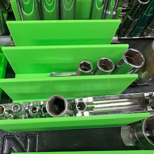 May include: Green plastic organizer with multiple compartments for storing various sizes of metal sockets. The organizer is filled with sockets of different sizes and lengths.