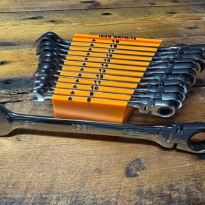 May include: A set of 12 ratcheting wrenches in a bright orange holder with size markings from 8 to 19. The wrenches are made of polished chrome steel and have a black handle.