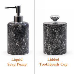 May include: A dark gray marble liquid soap pump with a silver-toned metal dispenser and a matching lidded toothbrush cup featuring a silver-toned knob handle. Both cylindrical bathroom accessories display a natural stone pattern with white veining.