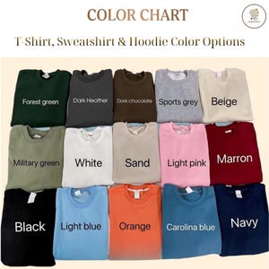 May include: A color chart displaying fifteen folded crewneck sweatshirts in various colors labeled Forest green, Dark Heather, Dark chocolate, Sports grey, Beige, Military green, White, Sand, Light pink, Marron, Black, Light blue, Orange, Carolina blue, and Navy.