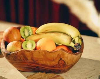 May include: A wooden bowl filled with fruit, including apples, kiwi, and bananas. The bowl has a natural wood grain and is a rustic style.