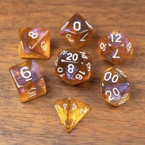 May include: Set of seven amber-colored polyhedral dice with white numbering, including a D4, D6, D8, D10, D12, D20, and a percentile die. The dice have a shimmering, iridescent effect and are arranged on a wooden surface.