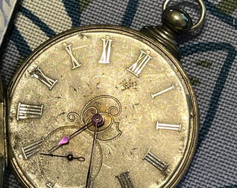 May include: Antique pocket watch with a silver-colored face and Roman numeral hour markers. The watch has a small subdial and ornate detailing around the hands. The watch is open, revealing the intricate design of the face.
