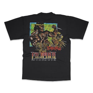 May include: Black t-shirt featuring a graphic of a muscular figure holding a knife, with the text "SABONG" and "FILIPINO STRENGTH" in a vintage style. The design includes a blue and green background.