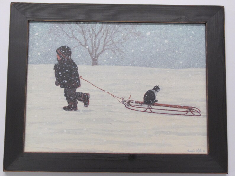 May include: A child wearing a black coat pulls a red sled through a snowy field. A black and white cat sits on the sled, looking ahead.