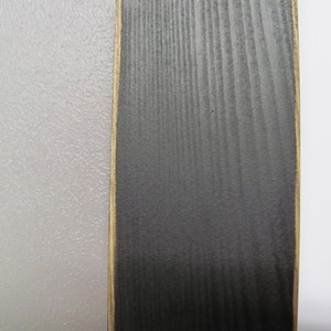 May include: A close-up of a vertical wood panel with a black stain and a gold-coloured border. The wood grain is visible.