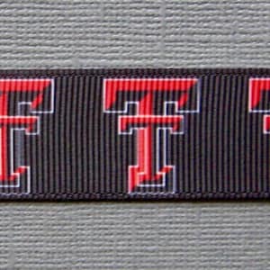 May include: Black ribbon featuring a repeating pattern of the letter "T" in red with a white outline. The ribbon has a textured appearance and is suitable for various crafting projects or decorative uses.