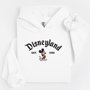 A white hoodie with the text "Disneyland EST. 1955" and a Mickey Mouse graphic printed on it.