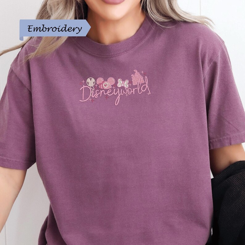 A person wearing a purple t-shirt with the text "Disneyworld" embroidered on it.