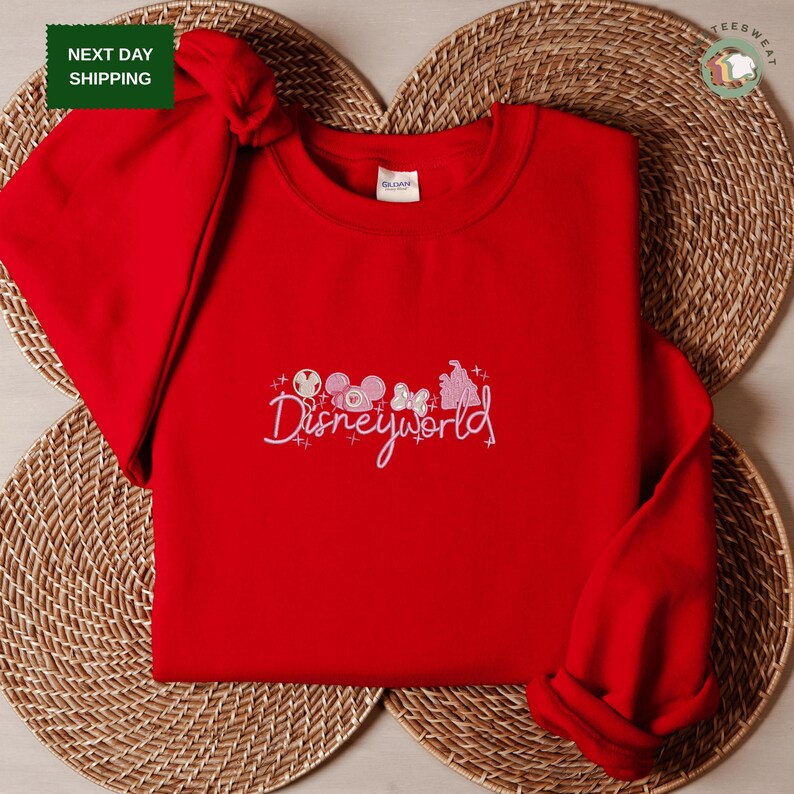 A red sweater with the text "Disneyworld" printed on it, placed on a woven placemat.