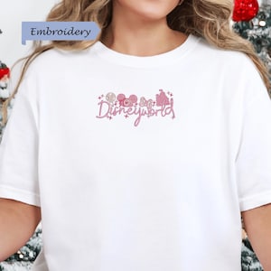 A person wearing a white t-shirt with the text "Disneyworld" embroidered on it.