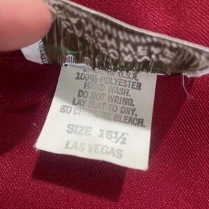 Puede incluir: Etiqueta de cuidado blanca con texto negro. La etiqueta dice: "100% Poli&eacute;ster, Lavar a mano, No escurrir, Secar plano, No usar blanqueador con cloro, Talla 16 1/2, Las Vegas."