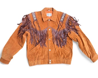 May include: A tan suede jacket with brown fringe and decorative beading on the shoulders. The jacket has a button-up front and a collar. The sleeves are long, and the jacket appears to be vintage.
