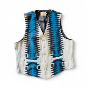 May include: A gray, blue, and black patterned vest with a V-neck and button closure. The vest features a geometric design in blue and black, with a gray background. It has two front pockets and a black lining.