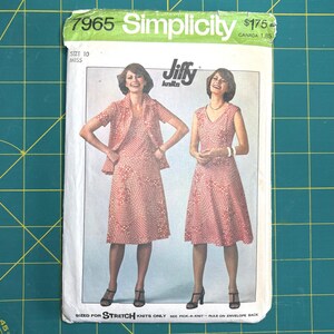 Könnte beinhalten: Vintage Simplicity Schnittmuster 7965 für ein Kleid und eine Jacke. Das Schnittmuster zeigt zwei Frauen, die das Kleid und die Jacke modellieren. Das Schnittmuster ist für eine Miss-Größe 10. Das Schnittmuster ist für Stretch-Strickwaren.