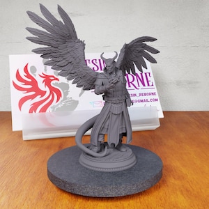 May include: Gray 3D printed miniature of a winged demon with a tail, horns, and a staff. The demon is wearing a long robe and has a serious expression. The miniature is on a round base.