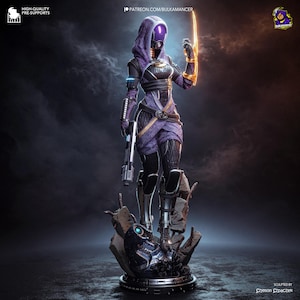 May include: A detailed figurine of a hooded character wearing a purple and black textured suit with a glowing visor. The character holds a silver pistol in one hand and a glowing yellow energy blade in the other, standing atop a base of rubble.