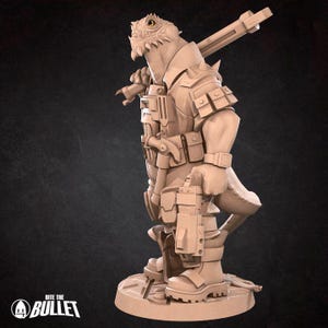 May include: A tan-colored figurine of a reptilian humanoid soldier, holding a rifle and a pistol. The figure is wearing a military-style uniform with pouches and boots. The figurine is standing on a circular base. The logo "Bite the Bullet" is visible.