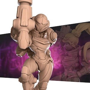 May include: A tan-colored figurine of a female character in futuristic armor, holding a large weapon. The figure has a detailed helmet and body armor, with a dynamic pose. A blurred image of the character is in the background.
