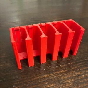 Puede incluir: Un organizador de pl&aacute;stico rojo con cinco ranuras para guardar objetos peque&ntilde;os, como dados o piezas de juego.