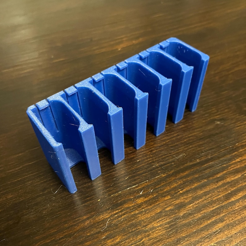 Puede incluir: Un organizador de pl&aacute;stico azul con seis ranuras para guardar objetos peque&ntilde;os, como dados o piezas de juego.