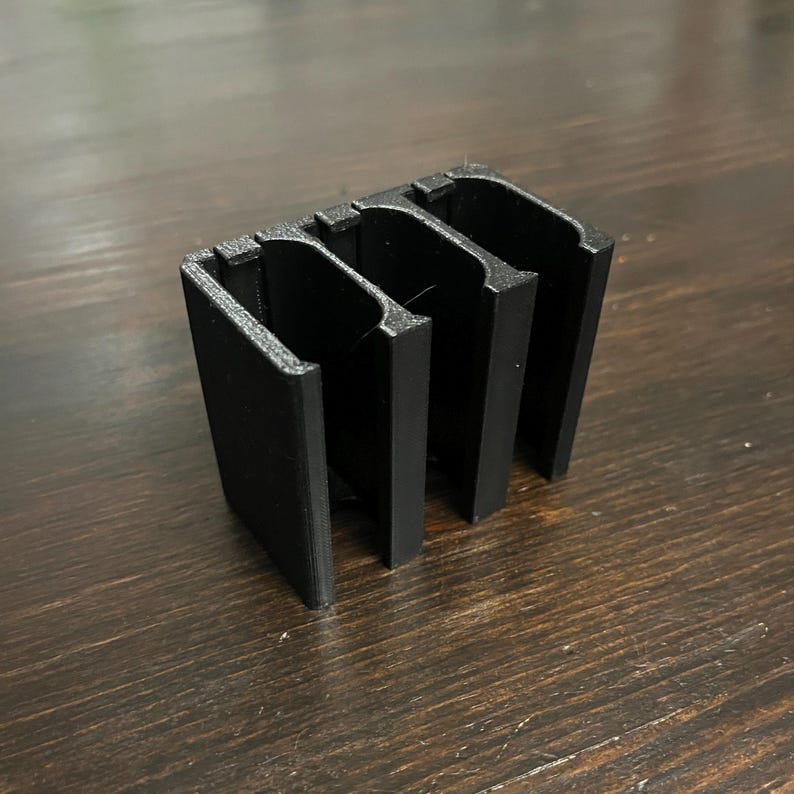 Puede incluir: Organizador de pl&aacute;stico negro impreso en 3D con tres ranuras.
