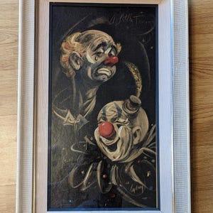 May include: Framed painting of two clowns, one sad and one happy. The sad clown has a tear running down his cheek and the happy clown is smiling. The painting is signed "Audrey" and has the text "A Little Tear" in the top right corner.