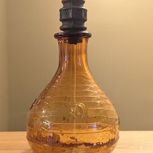 May include: A white ceramic mug with a black handle and the text "But First, Coffee" in a black, handwritten-style font. The mug is on a white surface.