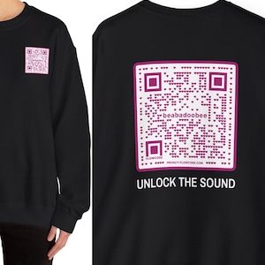 May include: Black sweatshirt with a pink QR code on the front and back. The QR code on the back has the text "beabadoobee" and "FLOWCODE PRIVACY.FLOWCODE.COM". The text "UNLOCK THE SOUND" is below the QR code.
