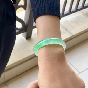 Puede incluir: Un brazalete de jade verde en la muñeca de una persona.